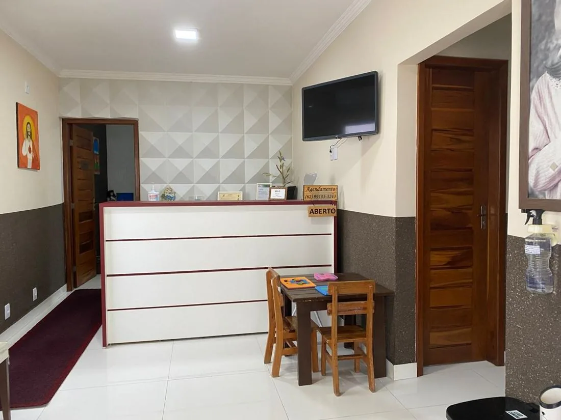Recepção da OSSS Odontologia com balcão, TV e mesinha infantil